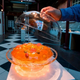 Person lifts glass lid off of orange Jell-O salad ring